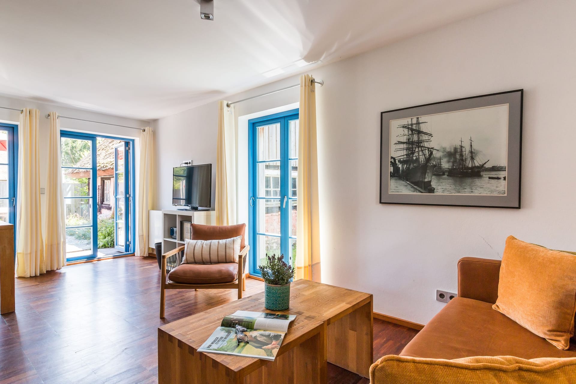 Helles Wohnzimmer mit großen Fenstern und TV