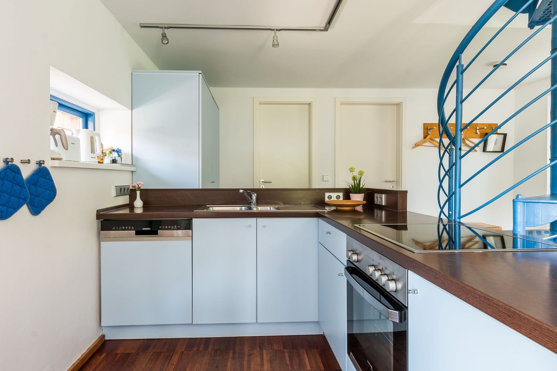 Moderne Küche mit hellblauen Schränken und Holzfußboden