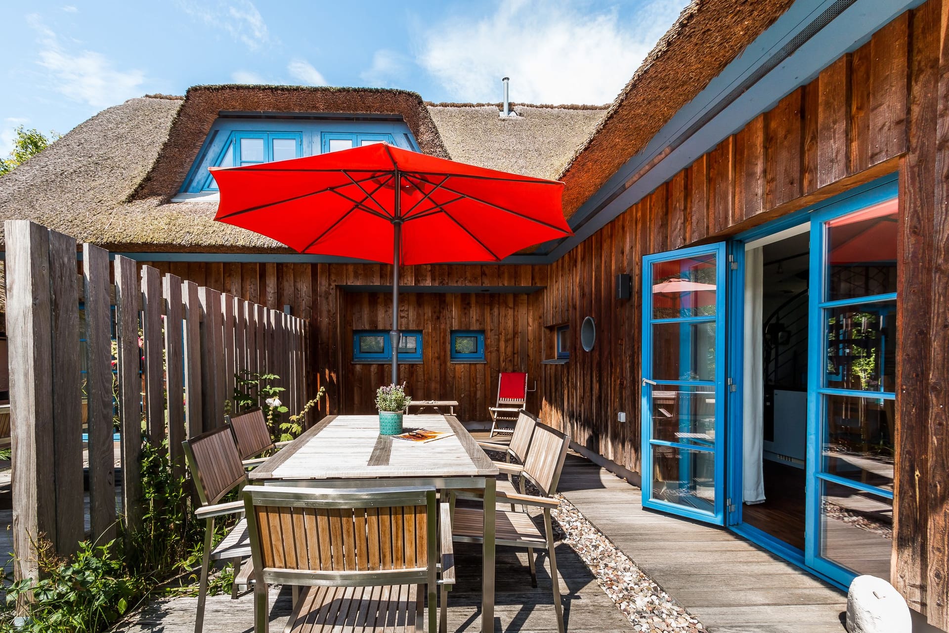 Terrasse mit Essbereich und rotem Sonnenschirm
