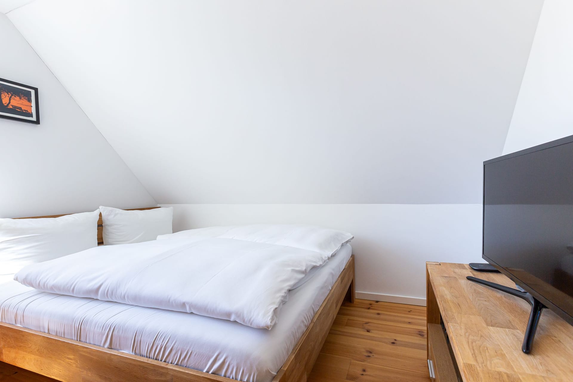 Helles Schlafzimmer mit Doppelbett und Fernseher