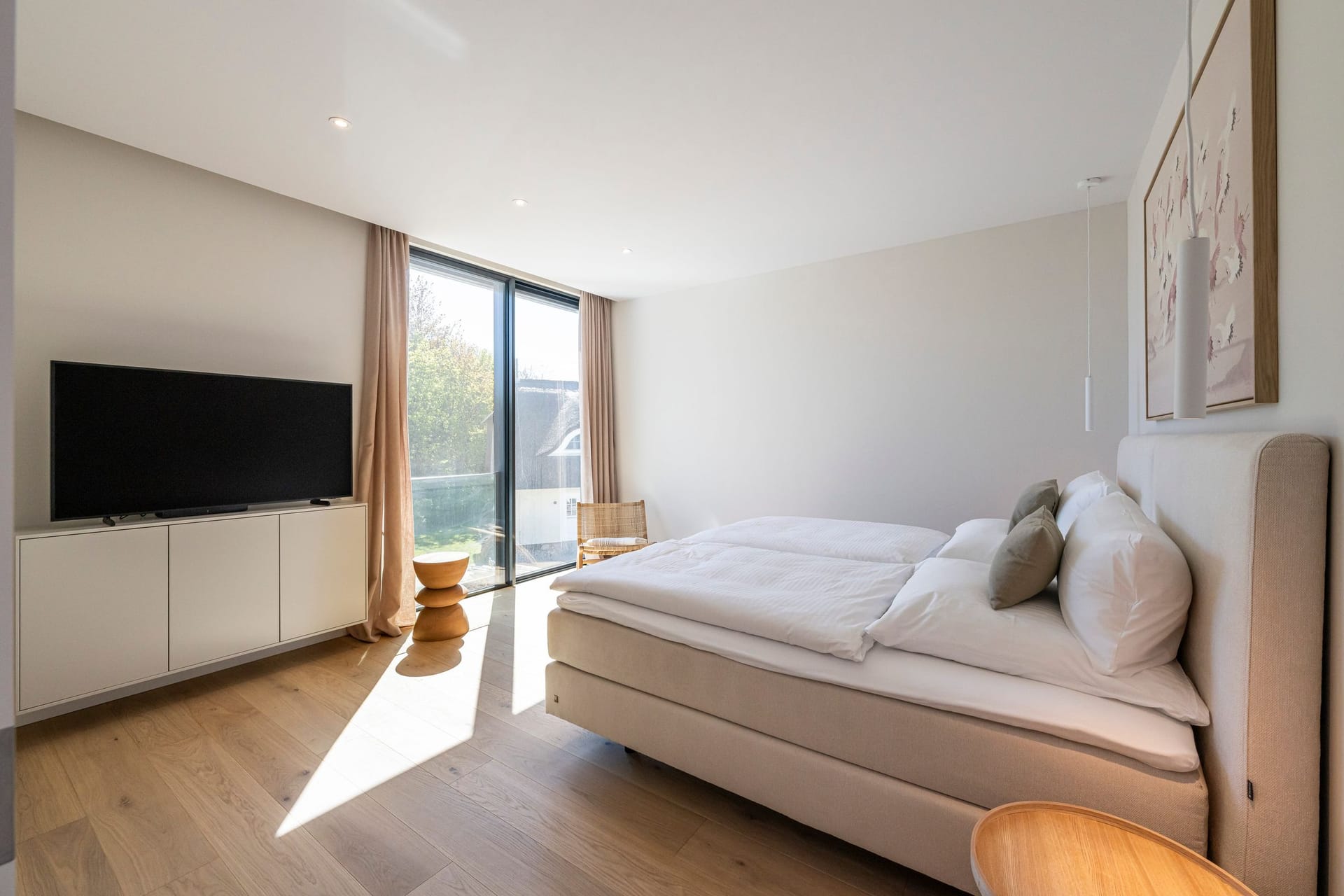 Helles Schlafzimmer mit Doppelbett und Fernseher