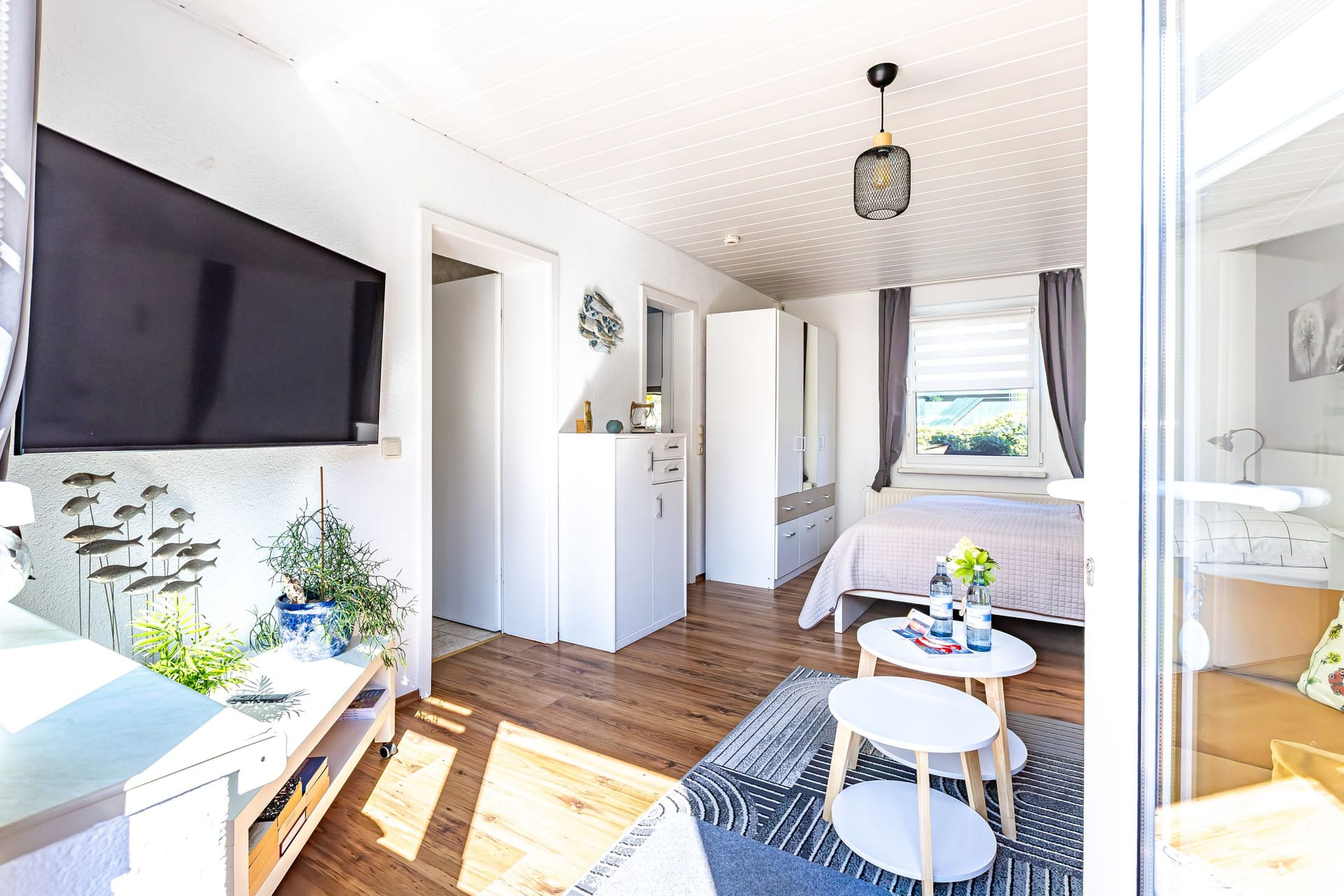 Helles Schlafzimmer mit Fernseher und Doppelbett
