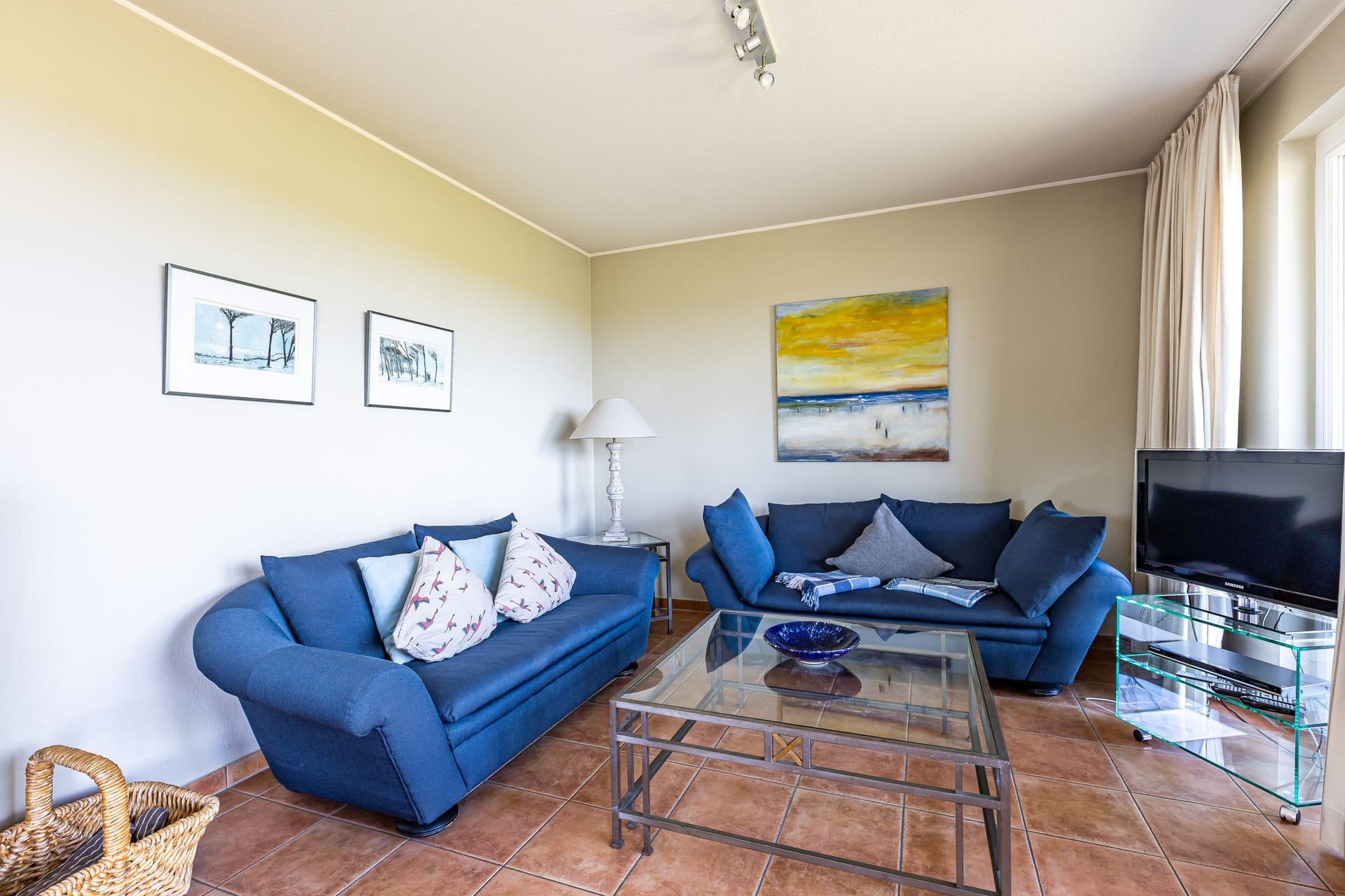 Helles Wohnzimmer mit blauen Sofas und Glastisch