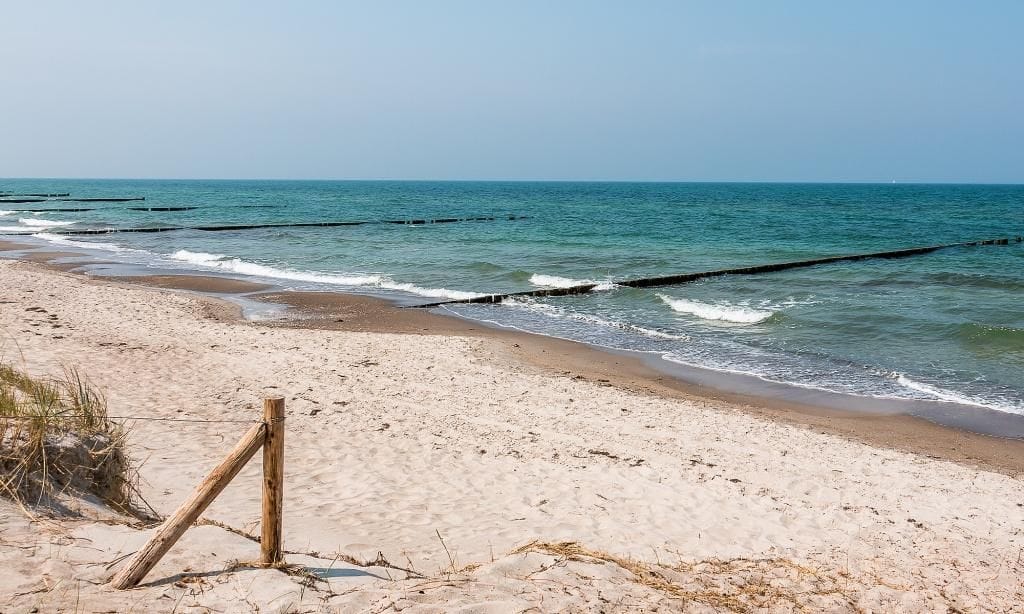 Strand mit sanften Wellen und Holzpfählen