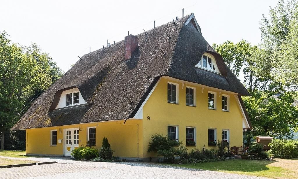 Außenansicht eines gelben Hauses mit Reetdach