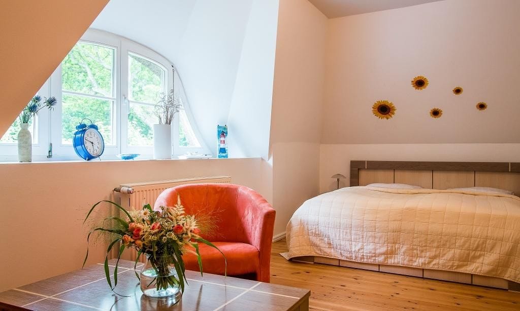 Schlafzimmer mit rotem Sessel und natürlichem Licht.