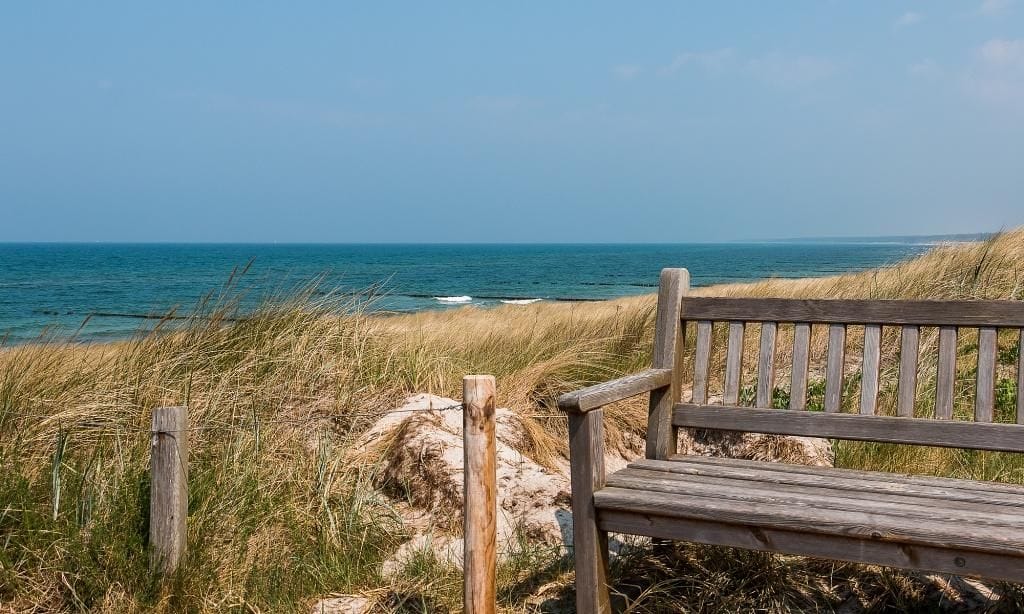 Blick auf das Meer von einer Bank am Strand