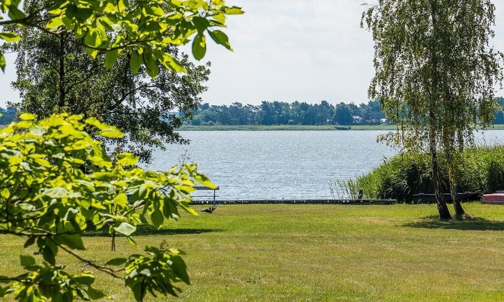 Blick auf einen ruhigen See mit grünem Ufer
