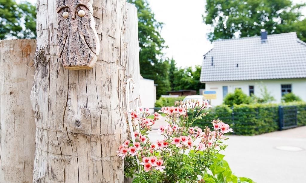 Holzpfosten mit Blumen und Gebäude im Hintergrund