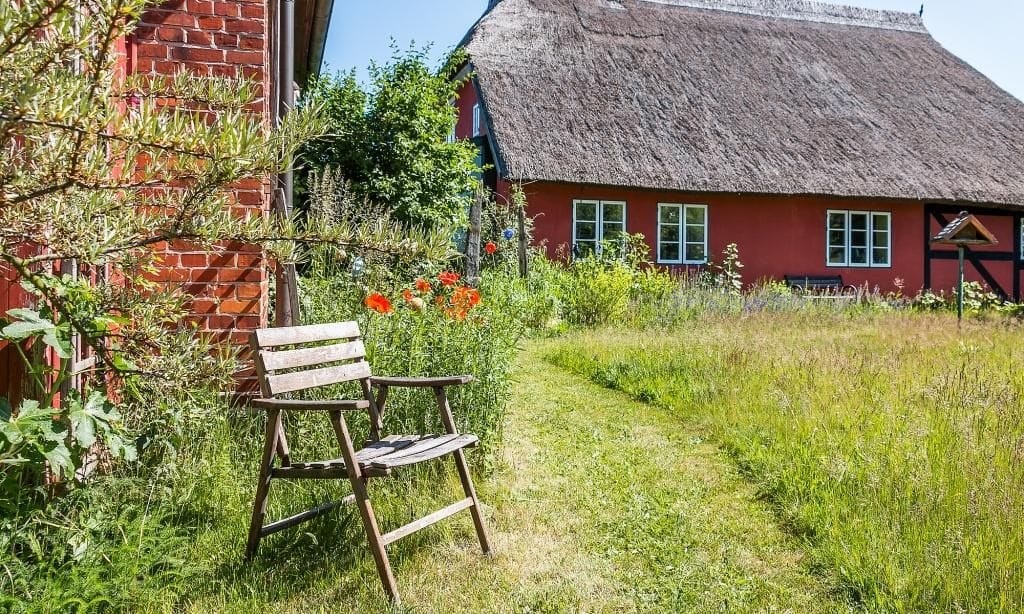 Außenansicht eines Hauses mit roter Fassade und Strohdach