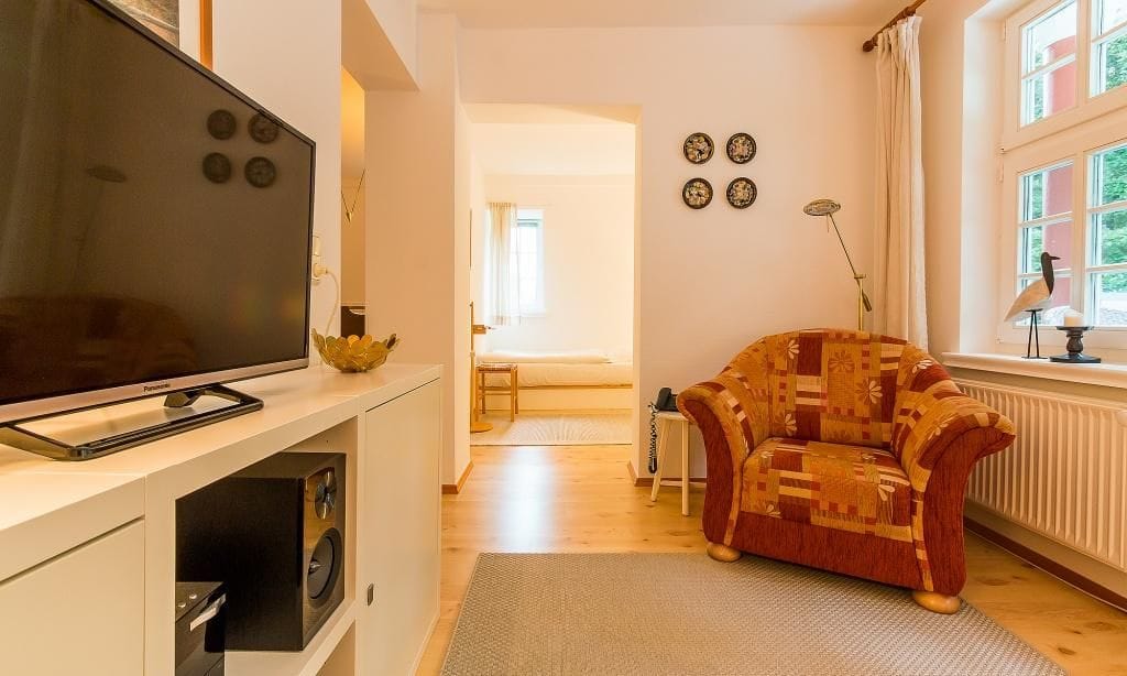 Gemütliches Wohnzimmer mit Fernseher und Sessel