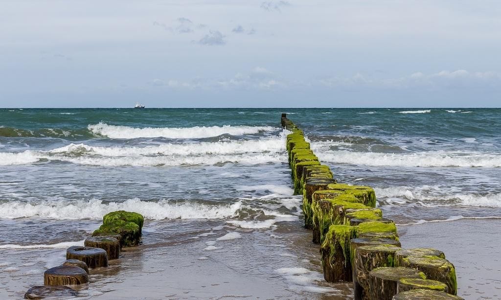 Strand mit Holzsteg und sanften Wellen
