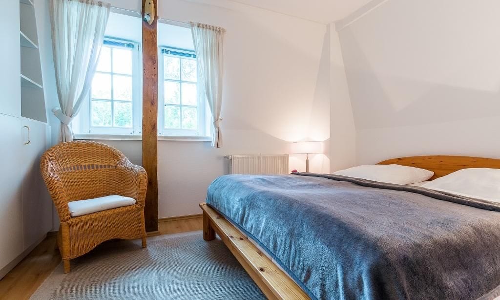 Schlafzimmer mit Doppelbett und hellen Fenstern