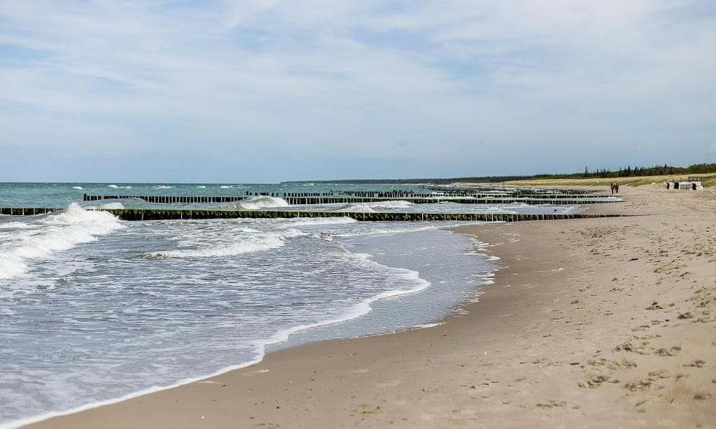 Strand mit Wellen und Holzpfählen
