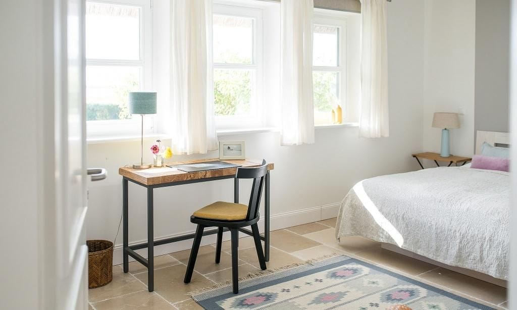 Helles Schlafzimmer mit Schreibtisch und Bett