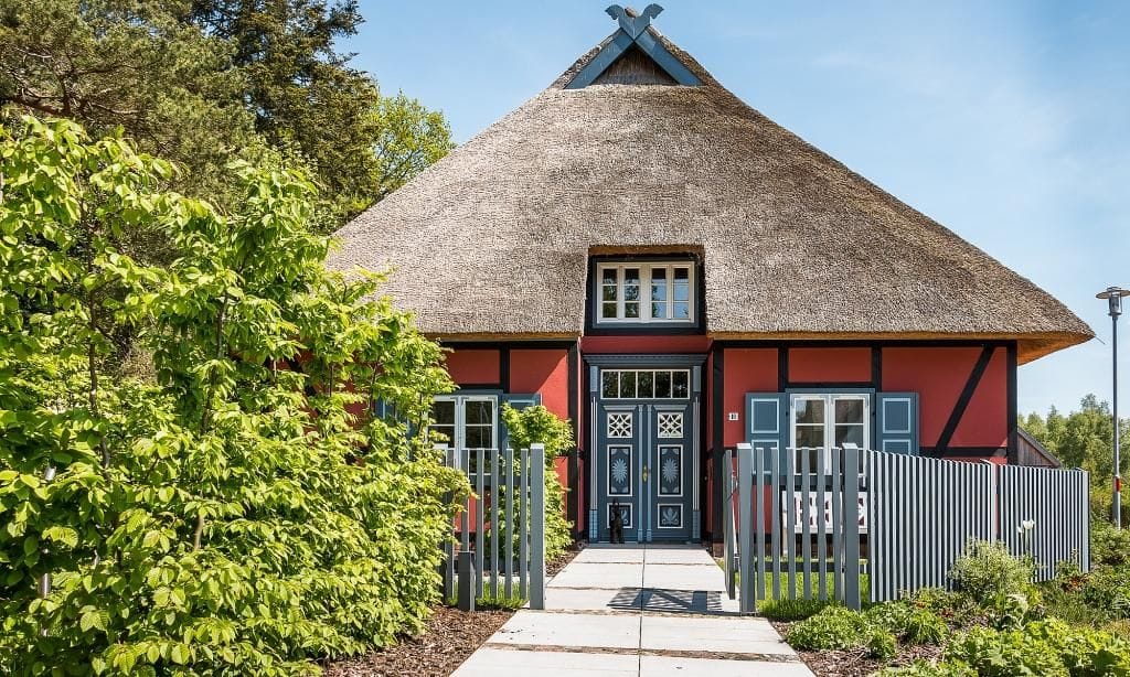Fassade eines Hauses mit Reetdach und Garten