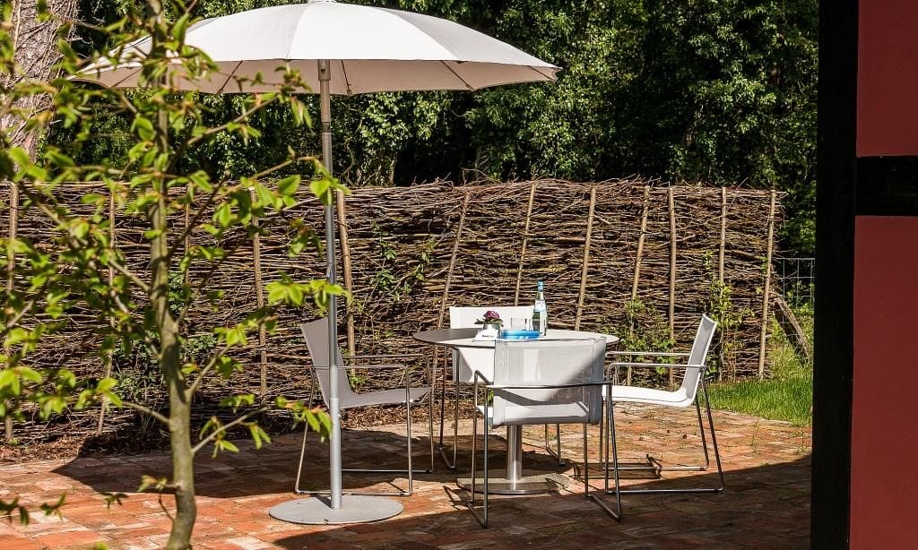 Terrasse mit Tisch und Stühlen unter Sonnenschirm