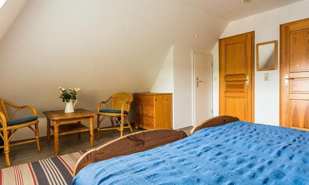 Schlafzimmer mit Bett und Rattanstühlen