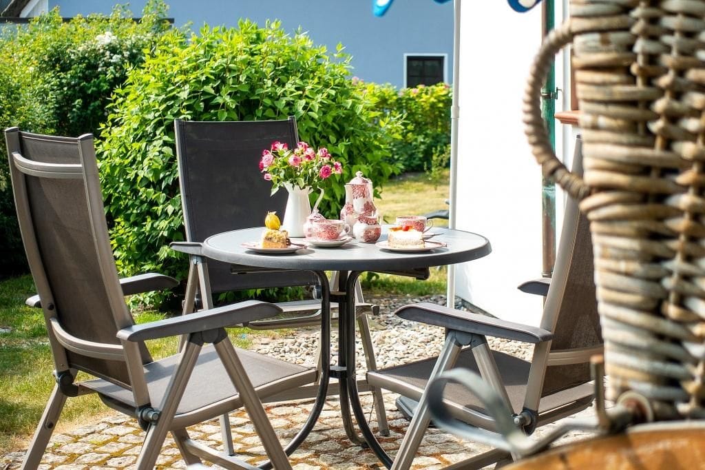 Terrasse mit Tisch und Stühlen in grünem Garten.
