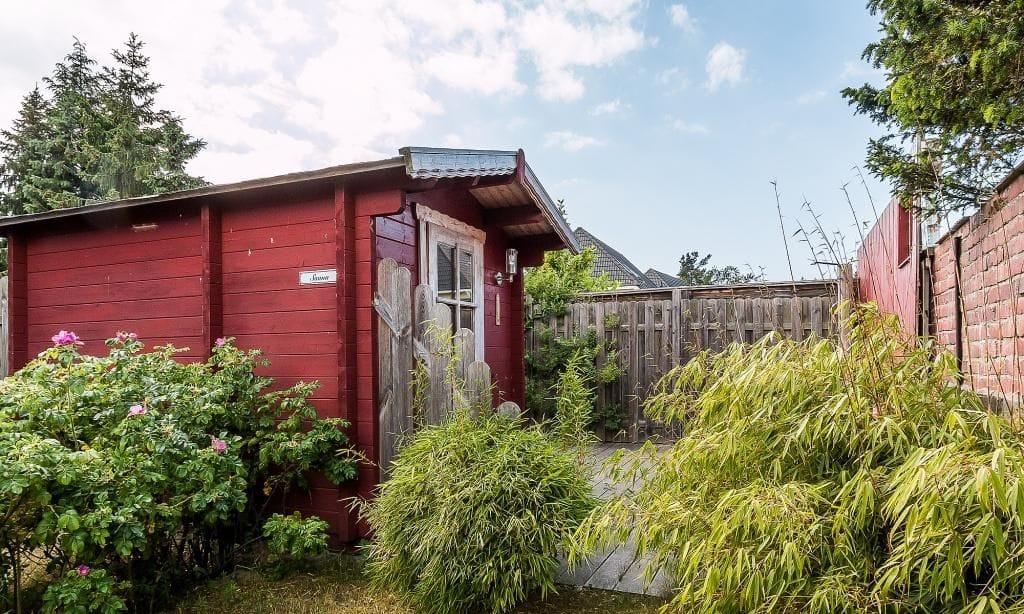 Außenansicht eines roten Holzhauses mit Garten