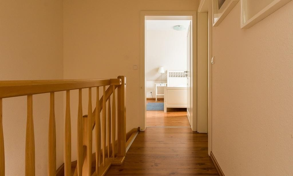 Flur mit Holzgeländer und Zugang zu einem Zimmer