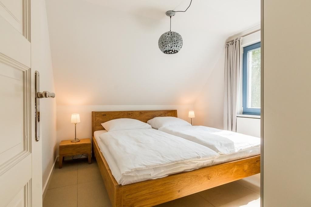 Ein Schlafzimmer mit einem Doppelbett und Nachttischen. Gemütliche Beleuchtung vorhanden.