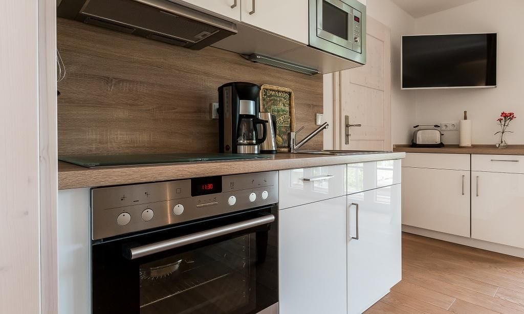 Moderne Küche mit weißen Schränken und Holztischplatte