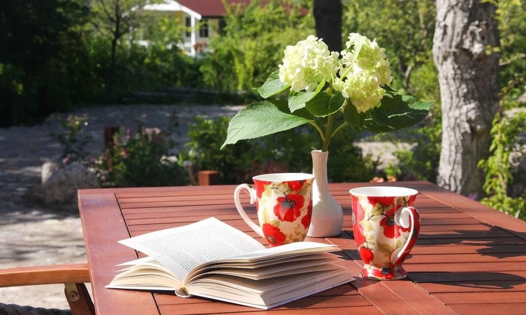Terrasse mit Tisch, Blumen und Kaffeetassen