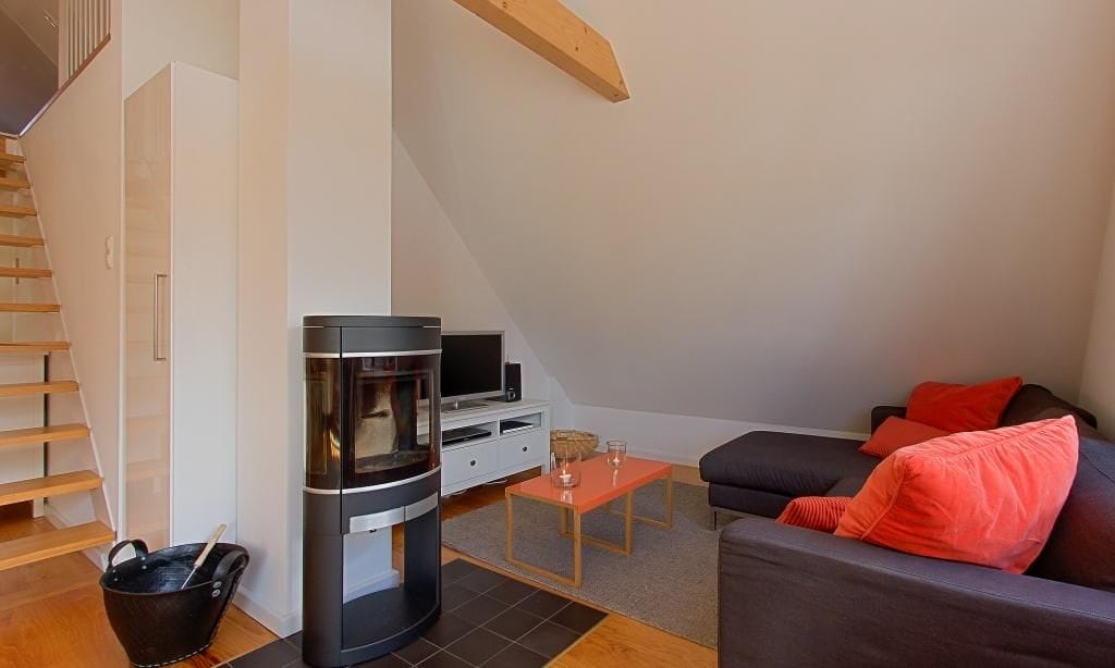 Heller Wohnbereich mit Sofa und Kaminofen.