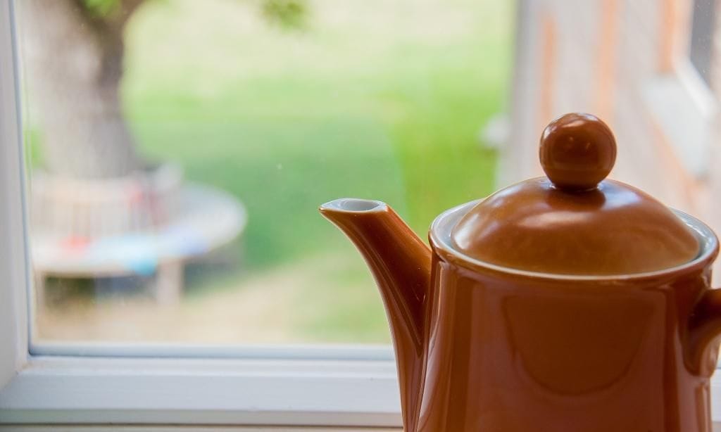 Teekanne auf dem Fensterbrett mit Gartenaussicht