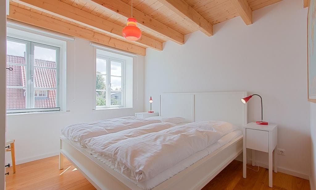 Helles Schlafzimmer mit Doppelbett und Fenstern