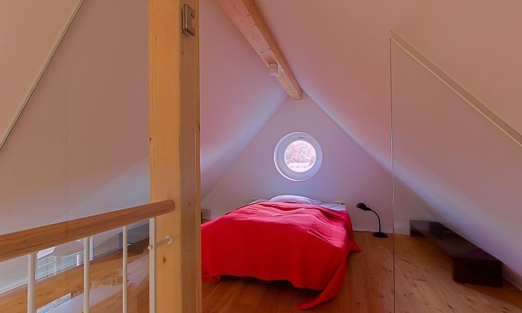 Schlafzimmer mit rotem Bett und Rundfenster