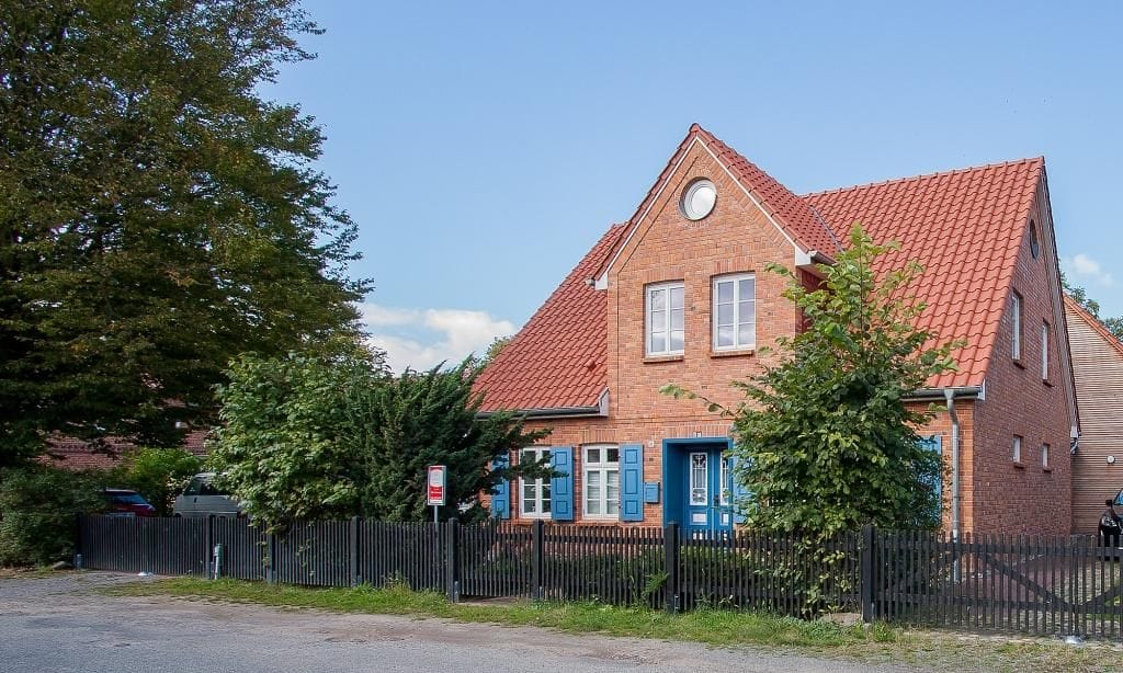 Außenansicht eines roten Ziegelhauses mit blauen Türen