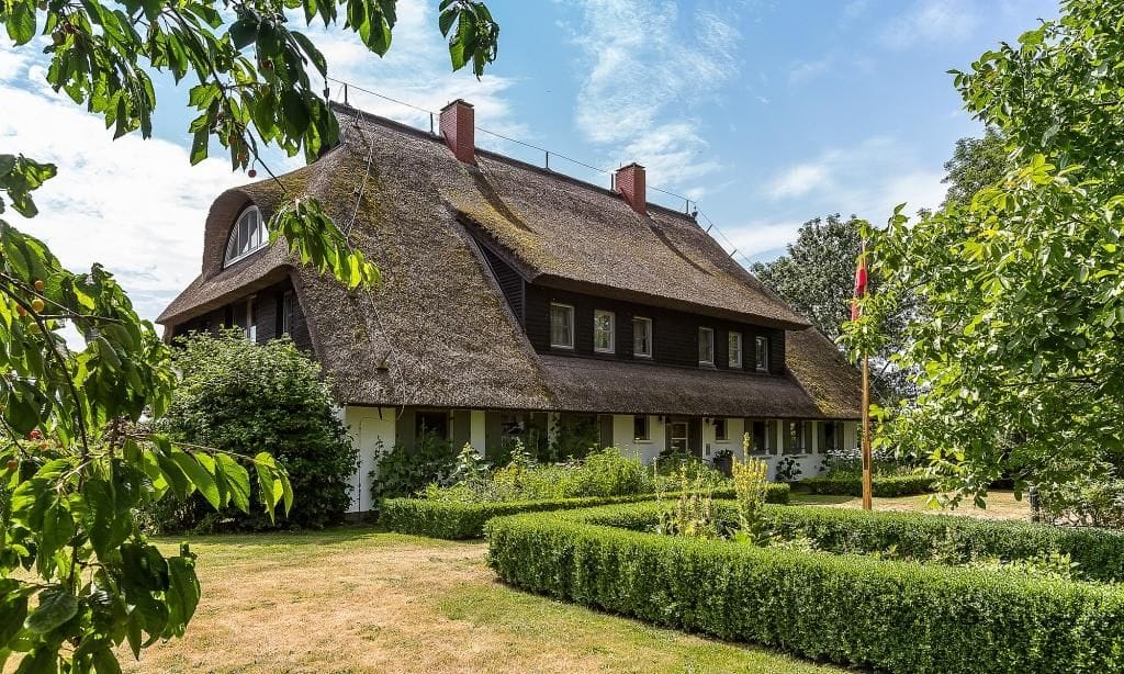 Außenansicht eines reetgedeckten Hauses mit Garten