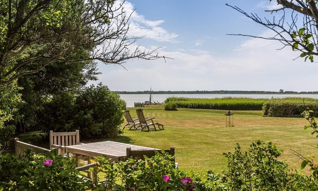 Strandblick mit Liegen und Tisch im Grünen