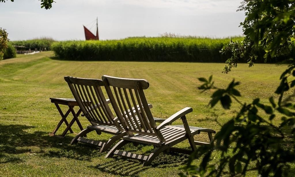 Terrasse mit Liegestühlen und Blick auf das grüne Feld