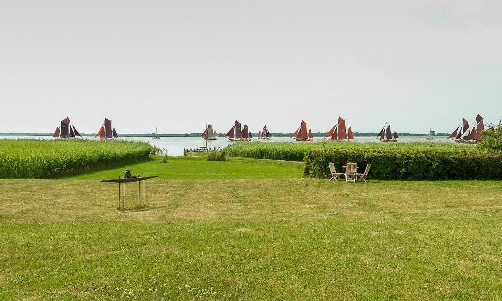 Grüne Wiese mit Blick auf das Wasser und Segelboote