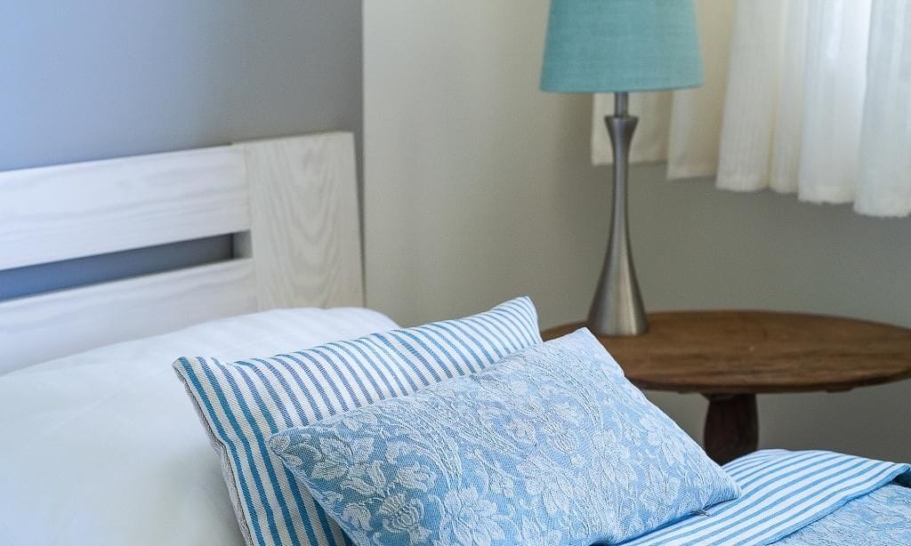 Schlafzimmer mit weißem Bett und blauen Kissen