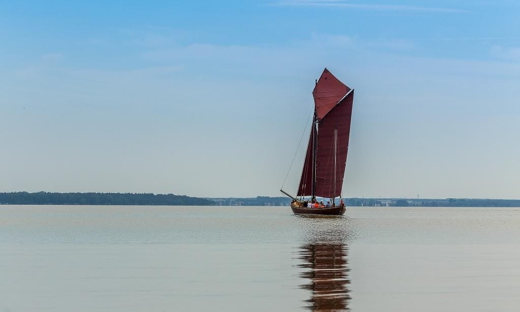 Boot mit rotem Segel auf ruhigem Wasser