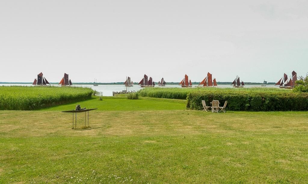 Wasseransicht mit Segelbooten und grüner Wiese
