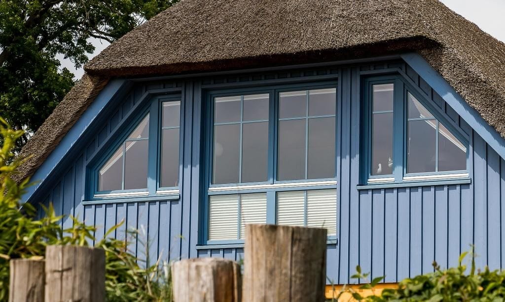Außenansicht eines Hauses mit blauem Holz und Reetdach