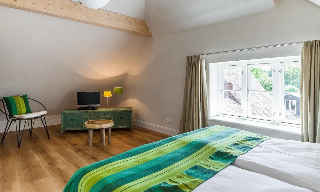 Helles Schlafzimmer mit Doppelbett und Sitzgelegenheit