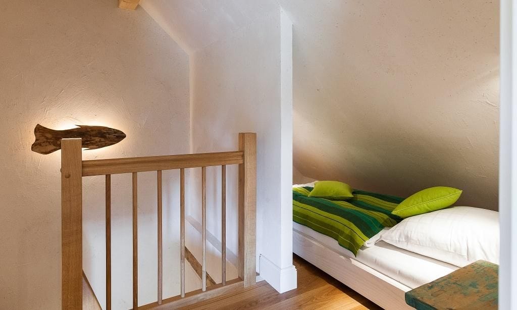 Schlafzimmer mit buntem Doppelbett und Holzgeländer