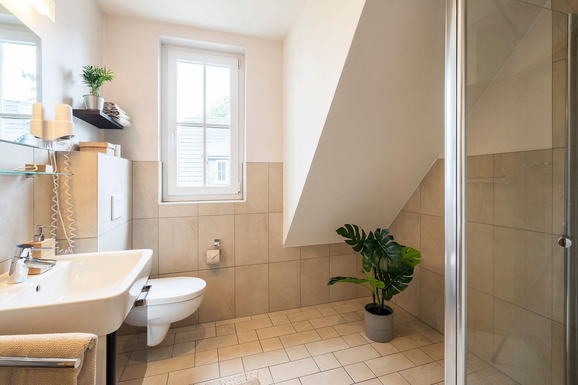 Elegantes Badezimmer mit Dusche, Waschbecken und Pflanzen.