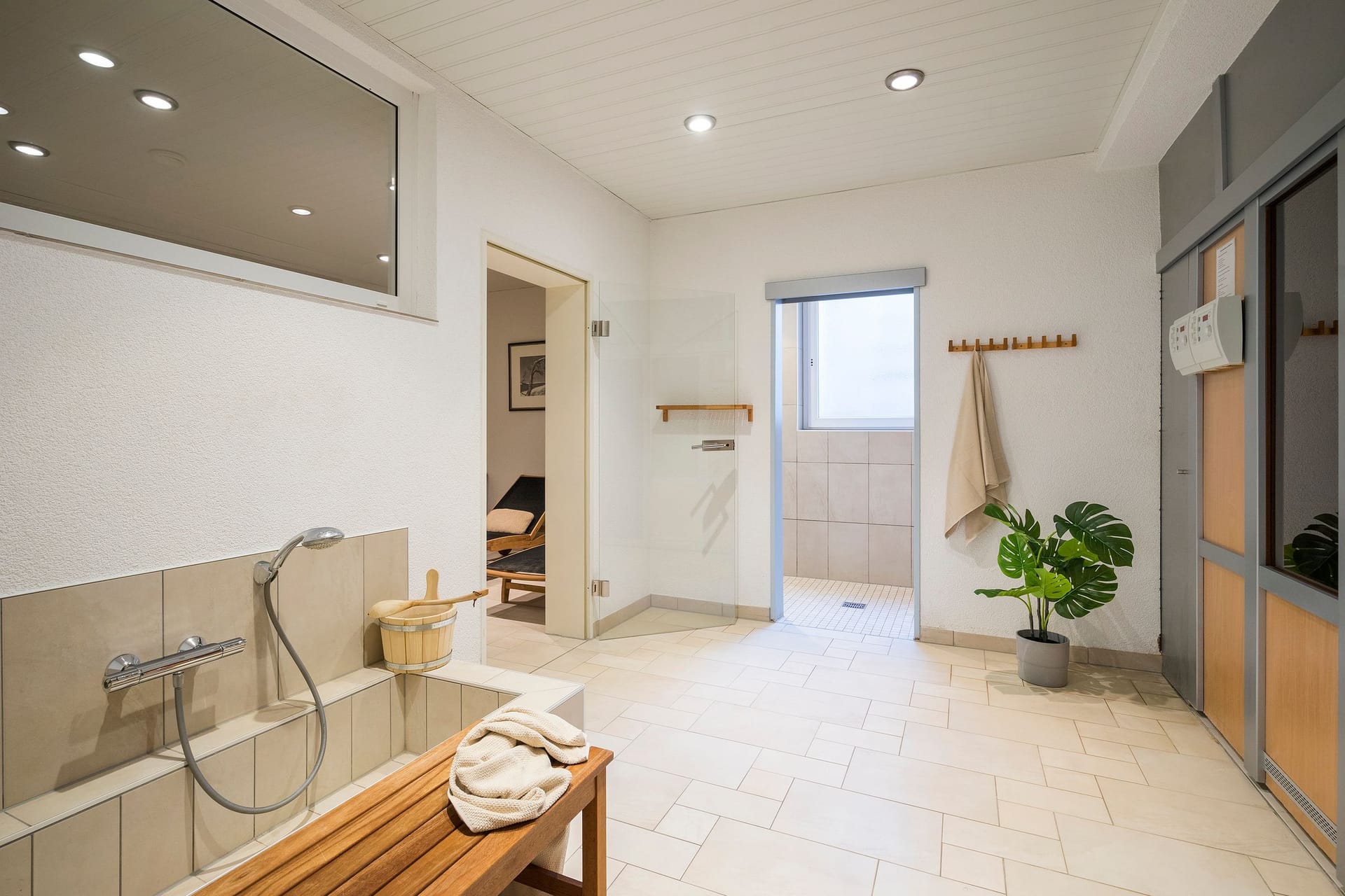Modernes Badezimmer mit Duschbereich und Holzbank.