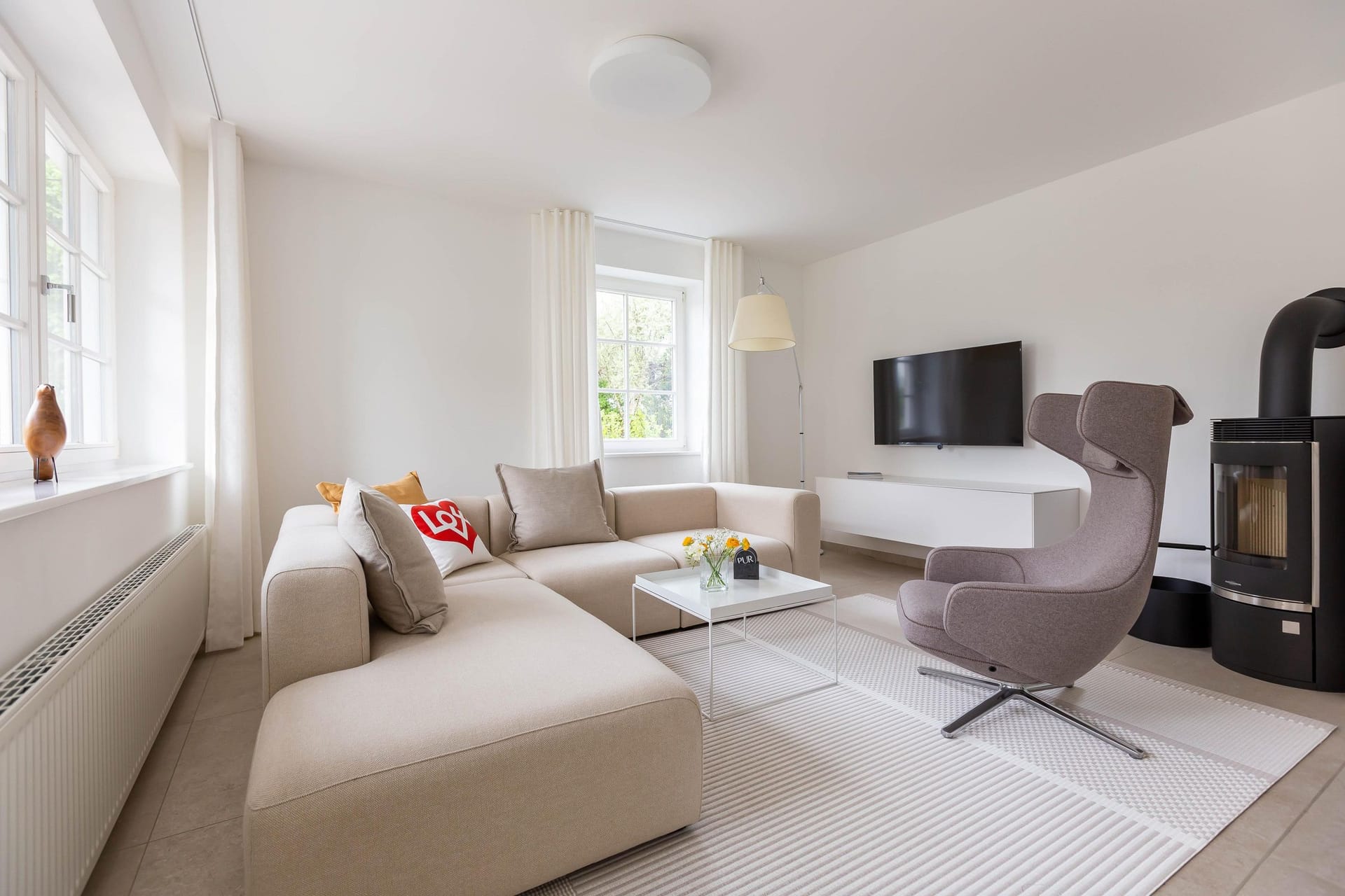 Modernes Wohnzimmer mit Sofa, Fernseher und Kamin.