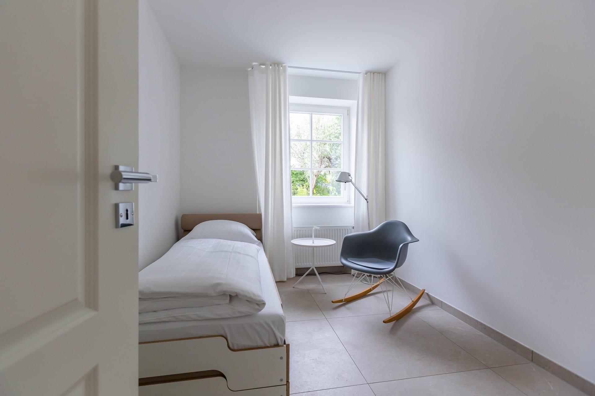 Helles Schlafzimmer mit Einzelbett und modernem Stuhl