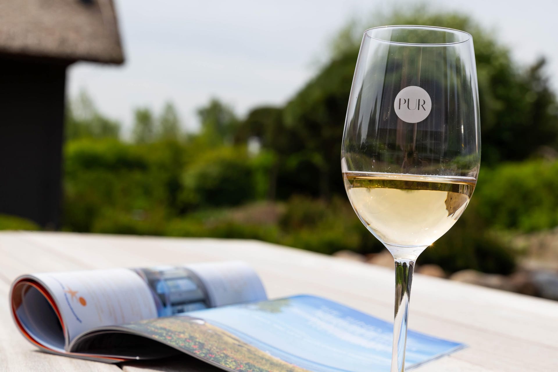 Elegantes Glas Weißwein auf Tisch mit Zeitschrift