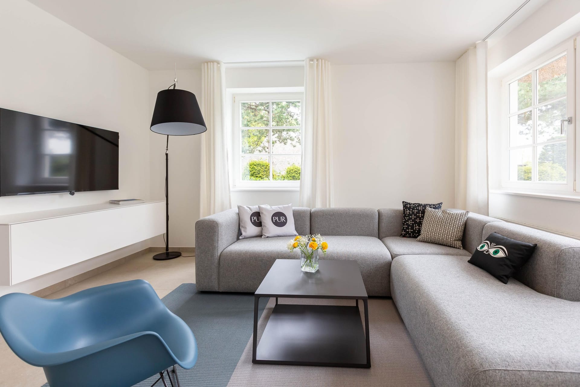 Helles Wohnzimmer mit grauer Couch und Fernseher