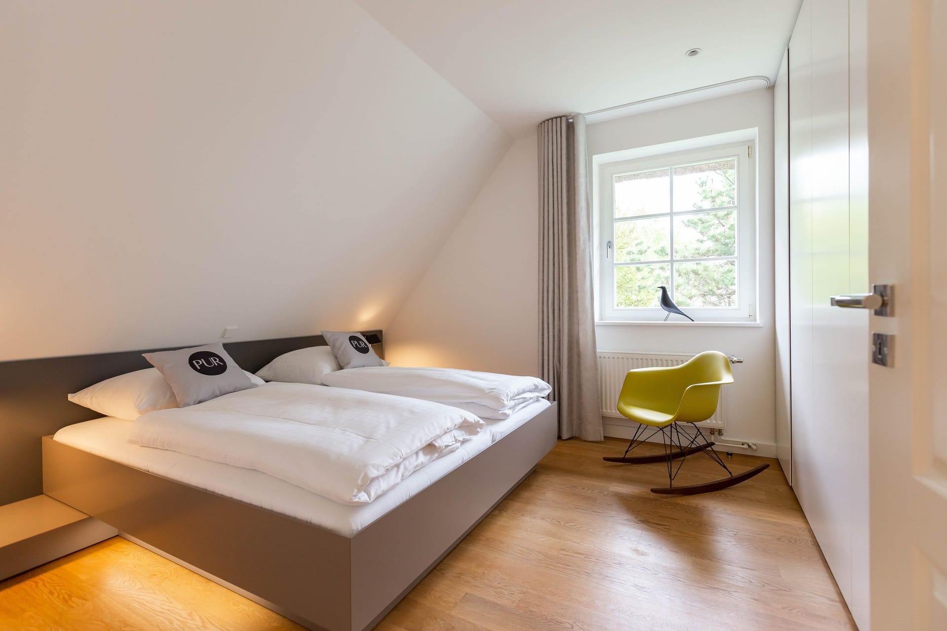 Schlafzimmer mit Doppelbett und modernem Stuhl